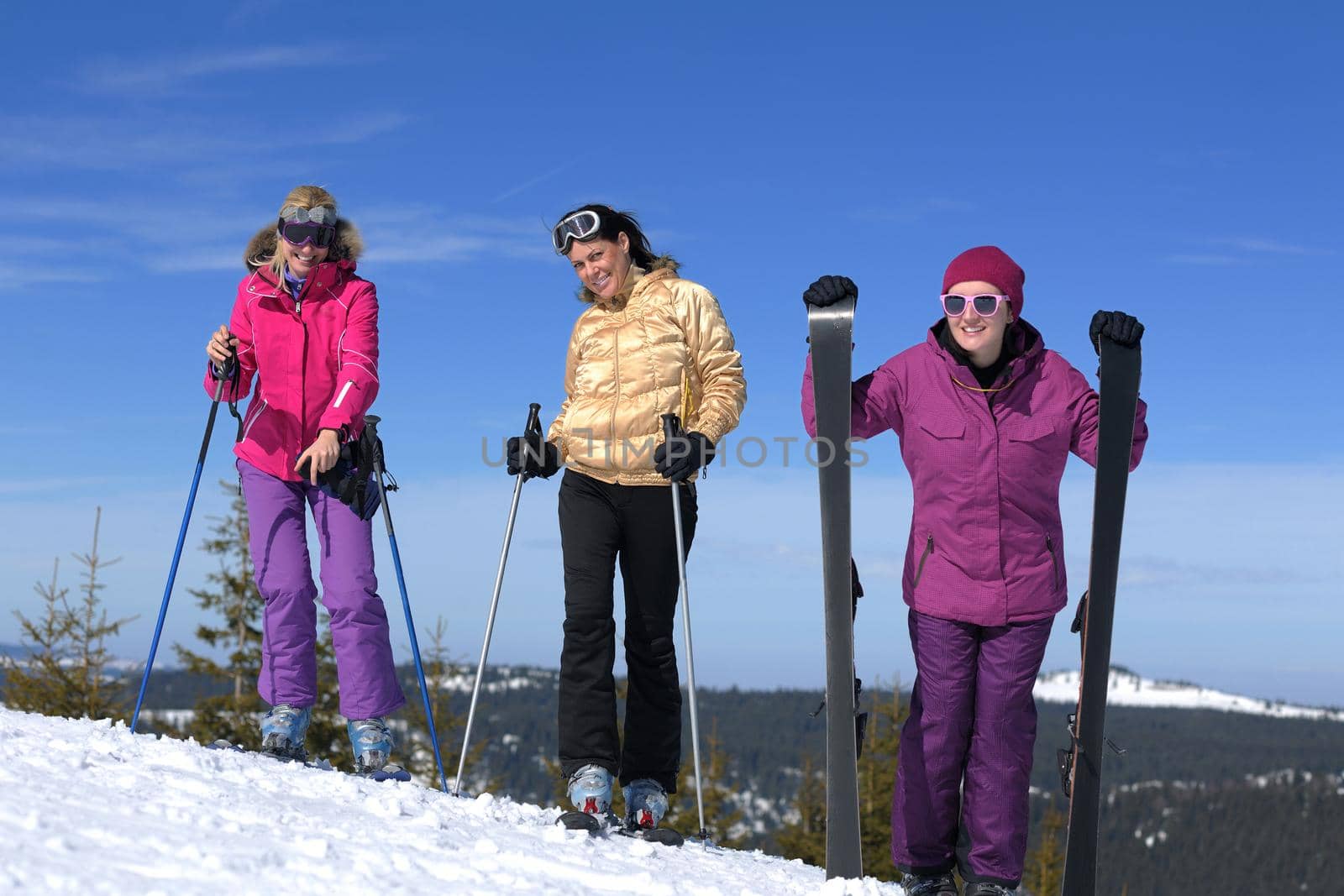 happy friends group of woman girls have fun at winter season at beautiful sunny  snow day with blue sky in background