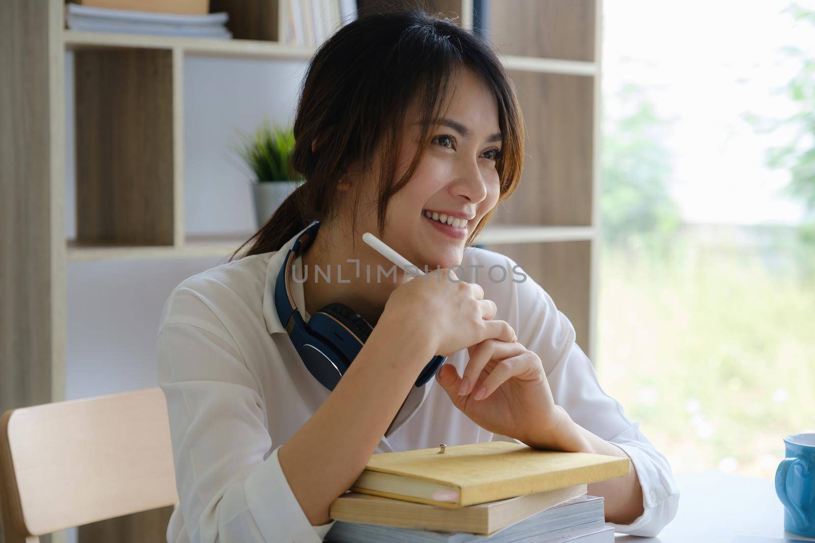 Portrait of cheerful asian woman with casual life on desk in home office. Concept of young business people working at home by itchaznong