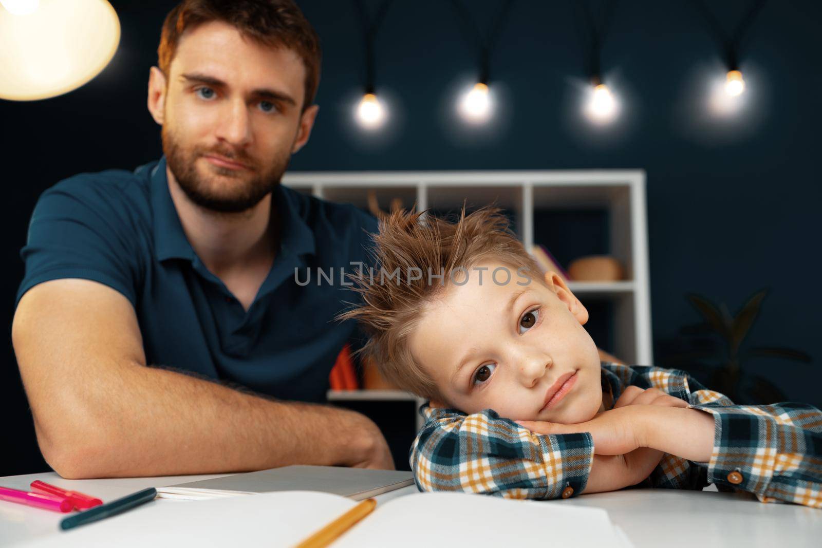 Dad and son doing school homework together sitting at the table