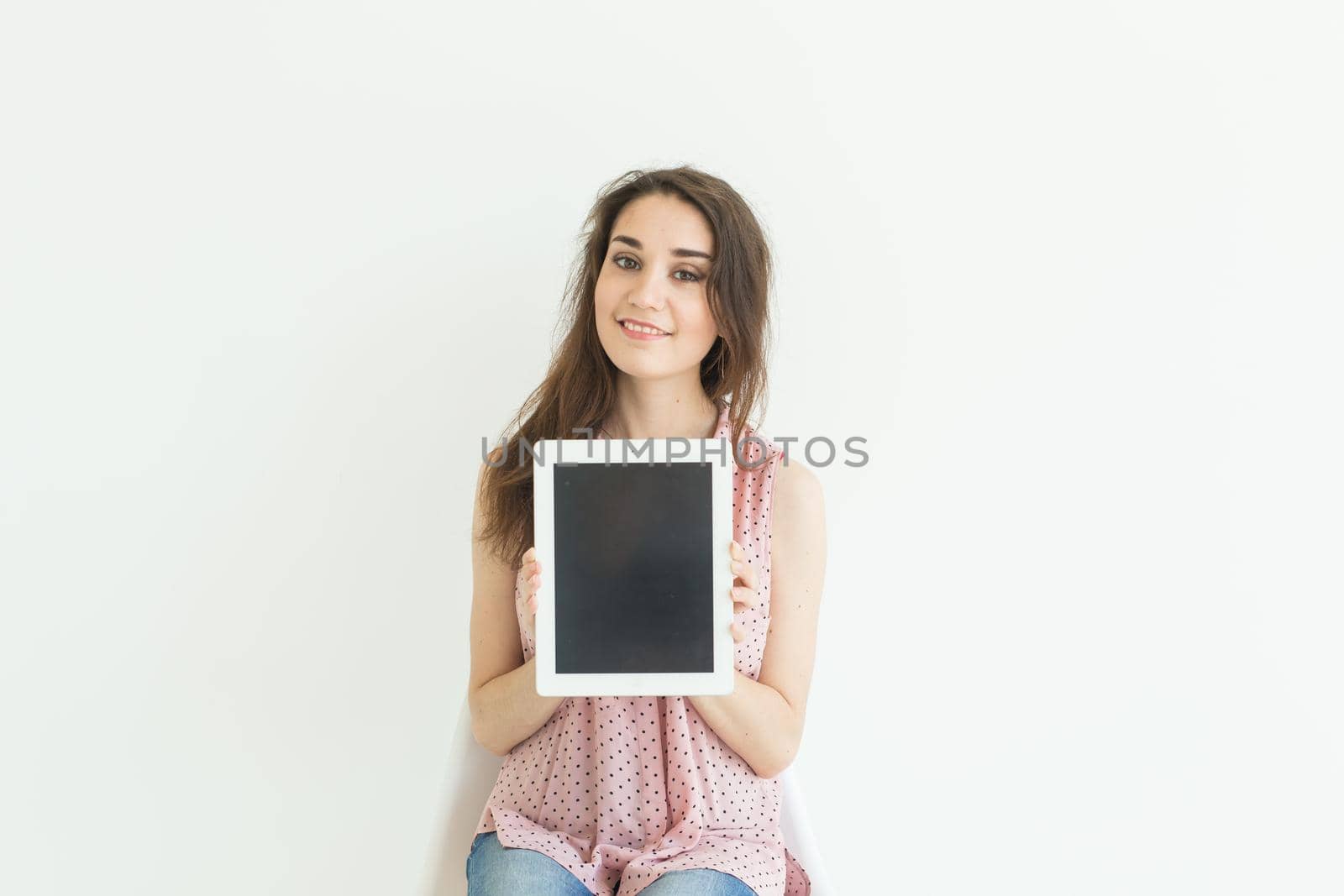 Business, technology and people concept - young woman showing empty screen in tablet on white background.