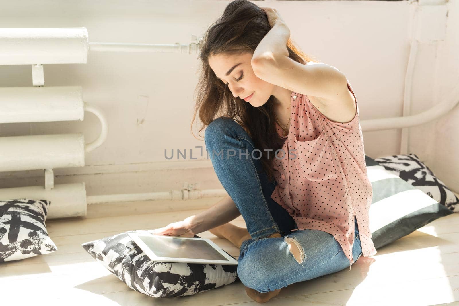 Leisure, technology and people concept - young brunette woman using tablet at home.