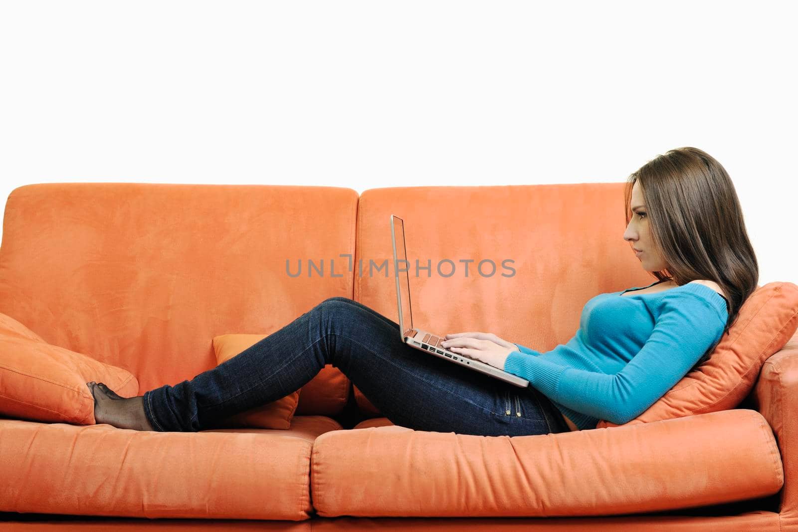 young business woman in casual clothes working on laptop computer on orange sofa isolated on white