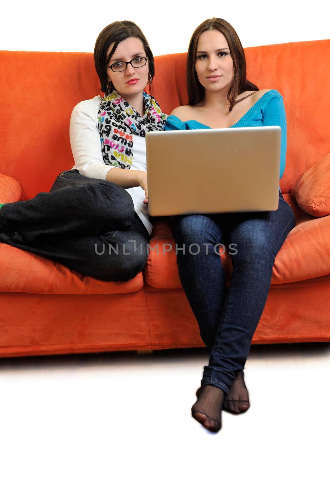 female friends relax and working on  laptop computer at home on orange sofa isolated on white backgrond