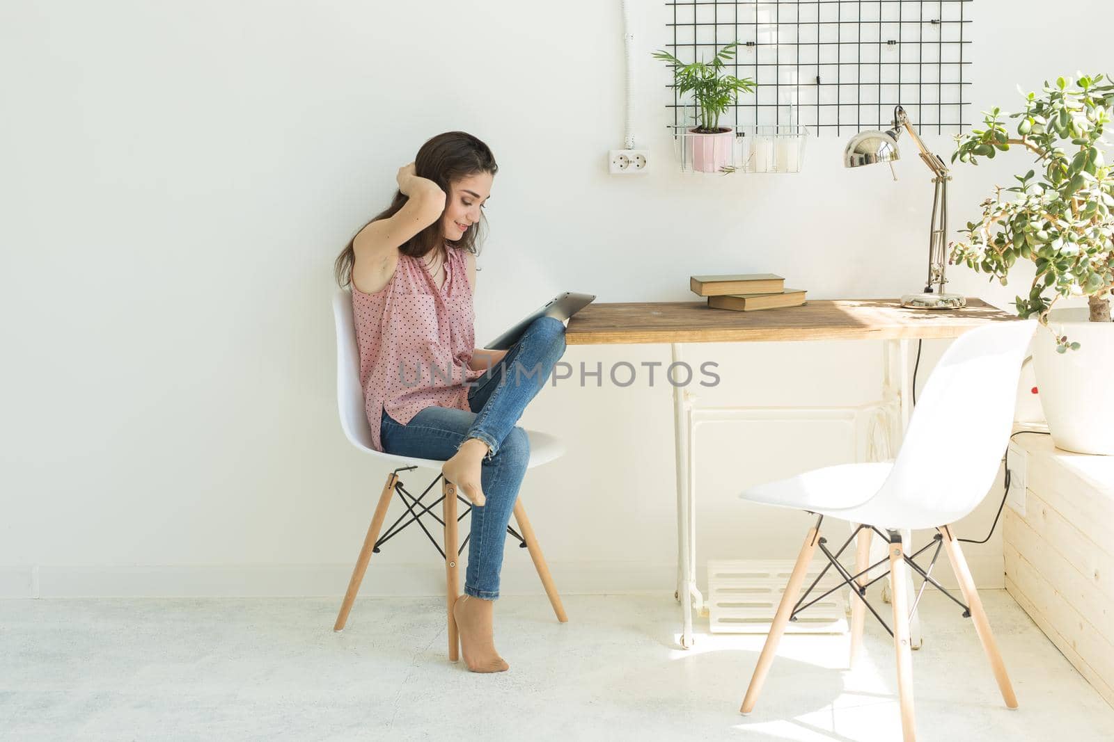 Leisure, technology and people concept - young brunette woman using tablet at home.