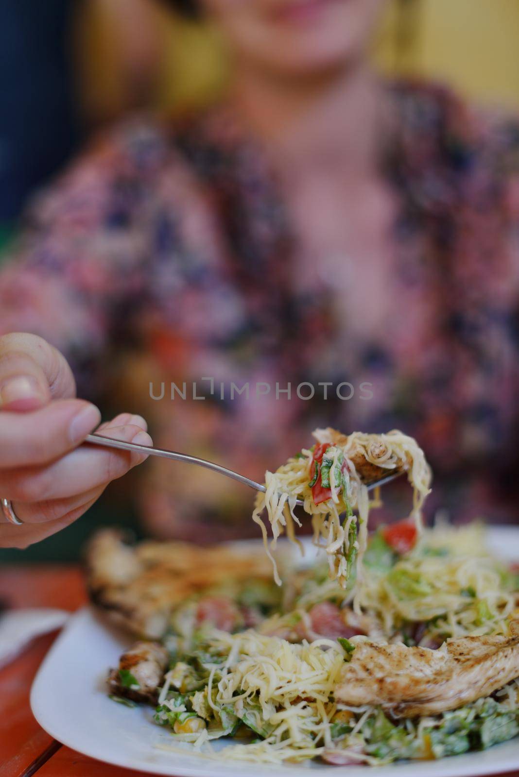woman eat tasty chicken salad with fresh vegetables and cheese in retro kitchen