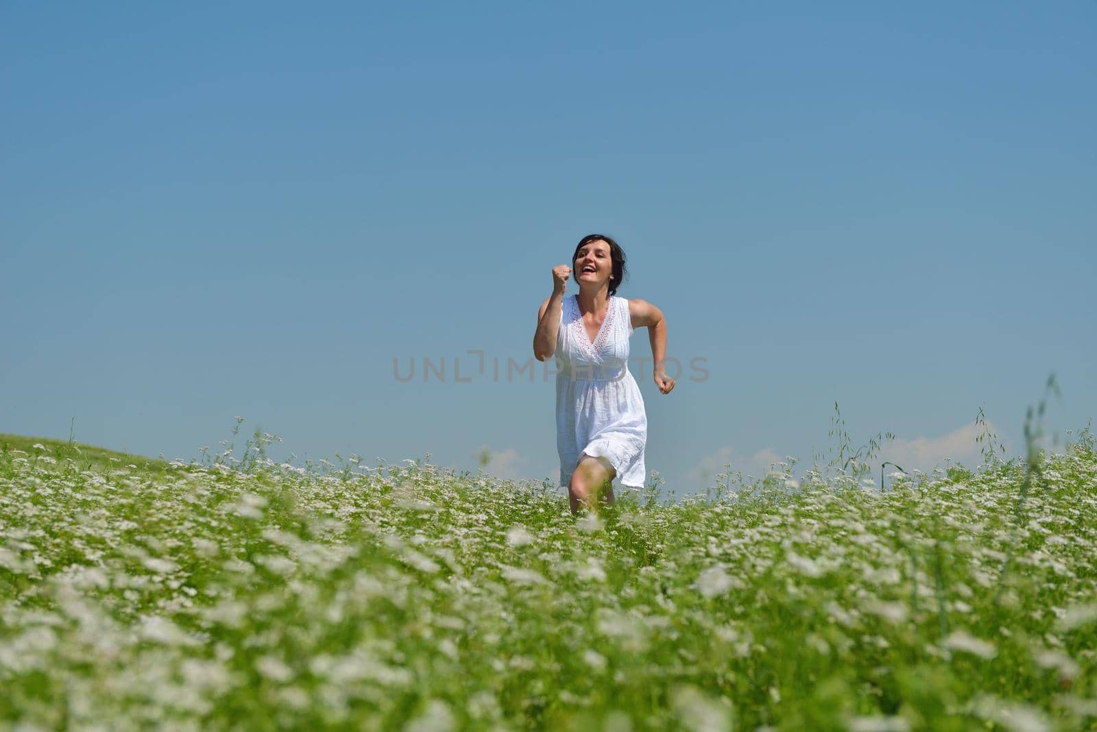 Young happy woman in green field with blue sky in background
