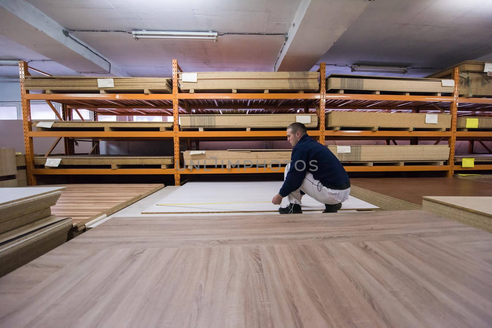 young man carpenter measuring wooden board for cutting while working in big modern carpentry High quality wood concept