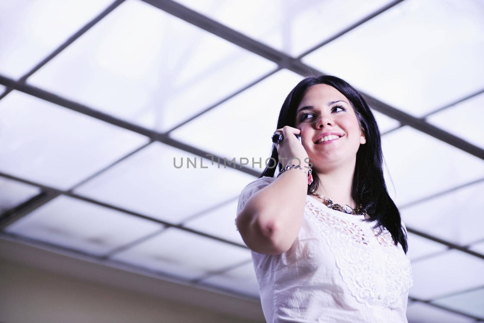 one young happy business woman talking by cellphone indoor in bright building