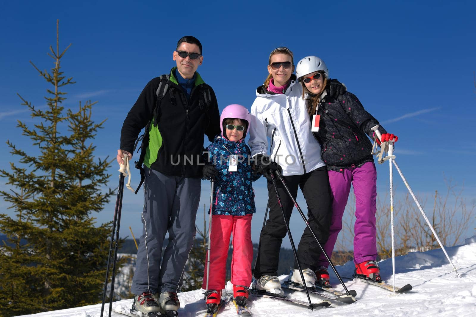 portrait of happy young family at beautiful winter sunny day with blue sky and snow in background