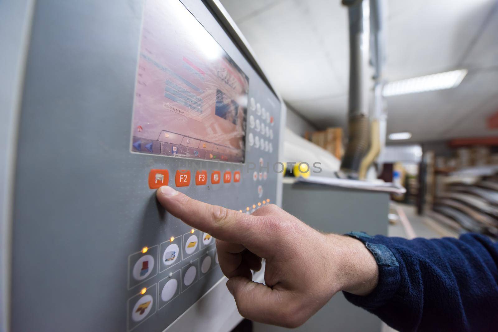 young carpenter calculating and programming a cnc wood working machine in workshop. wood worker preparing a computer program for CNC machine at big modern carpentry