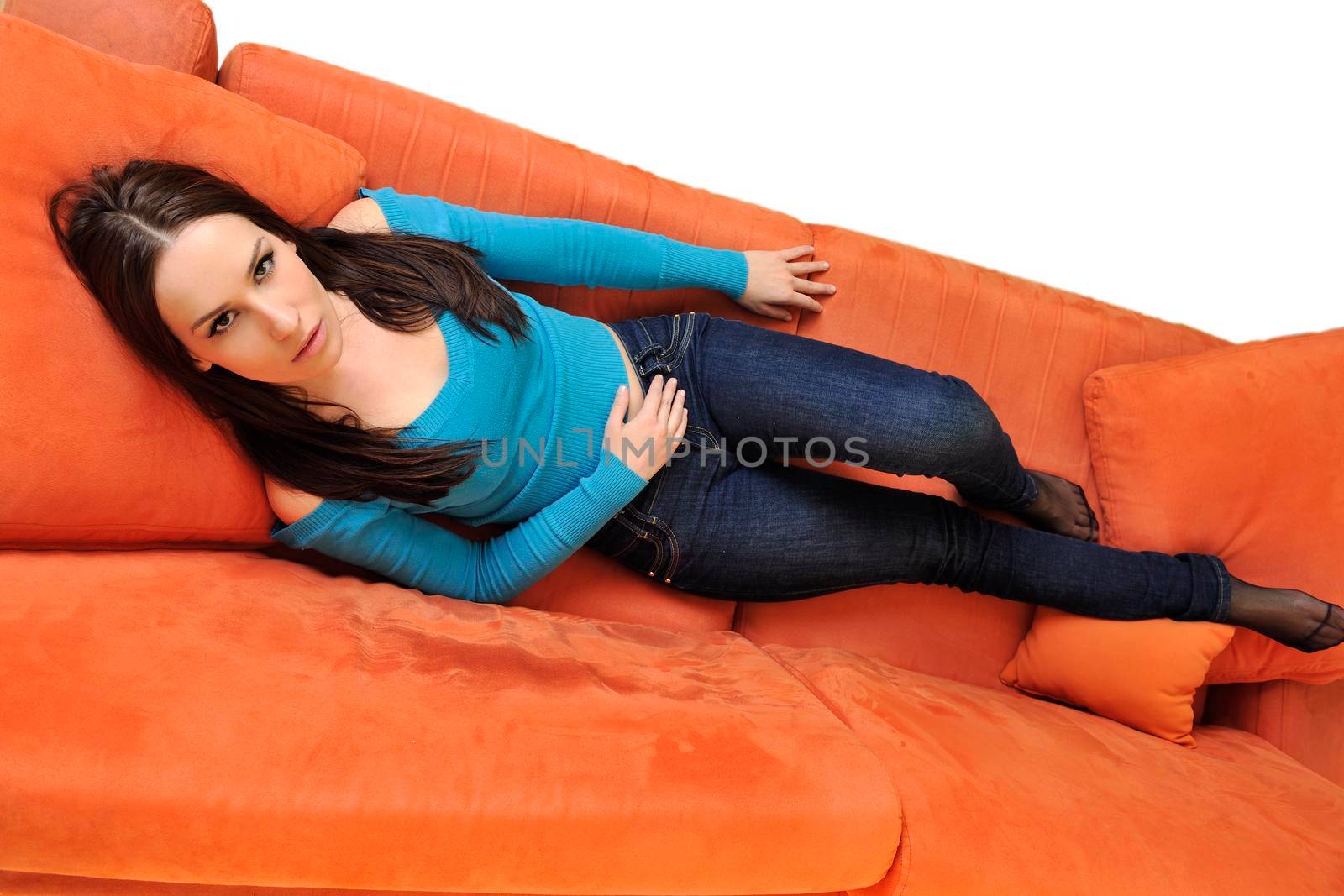 happy young woman relax on orange sofa  at home isolated on white background in studio