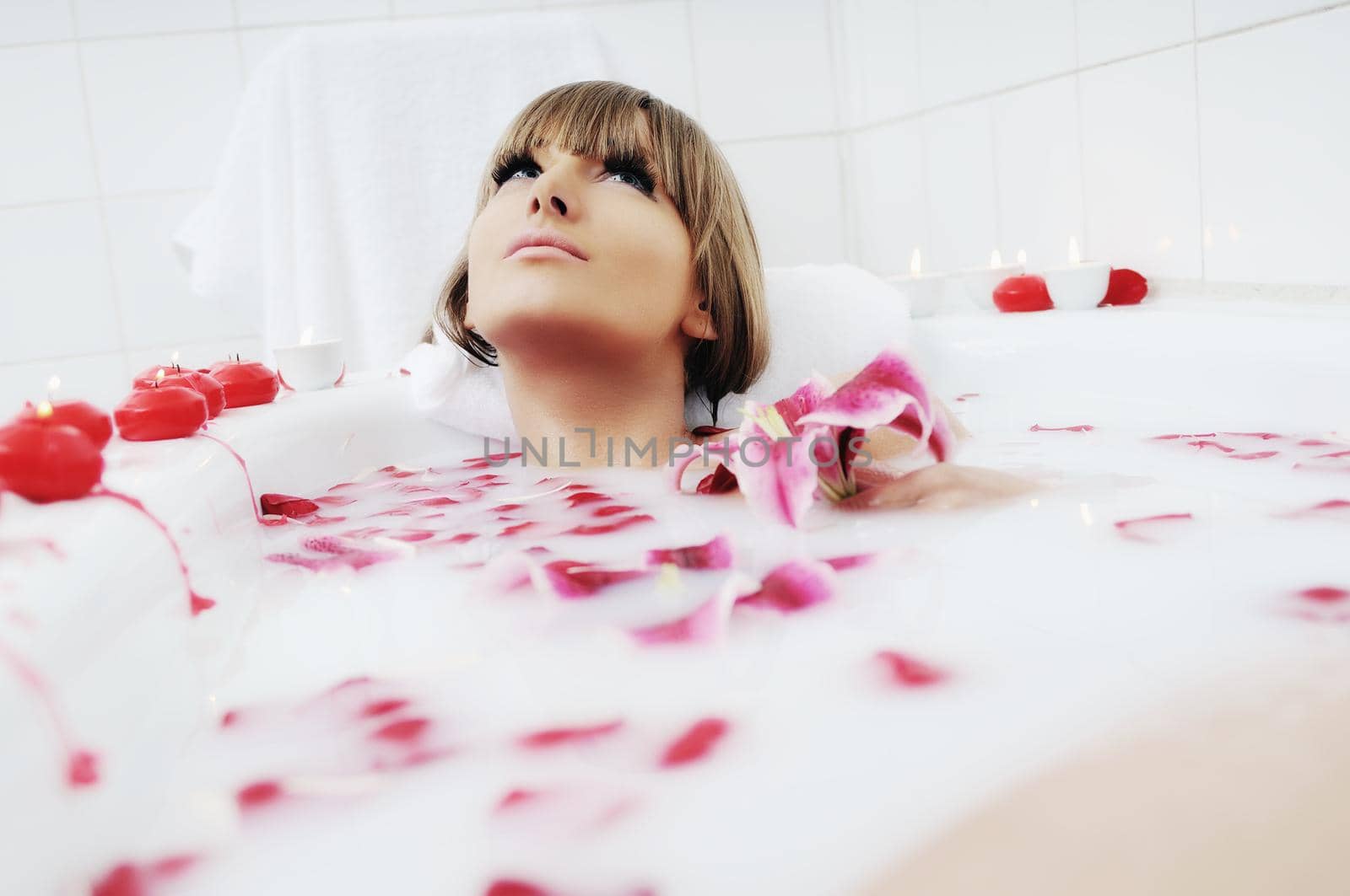 woman beauty spa and wellness treathment with red flower petals in bath