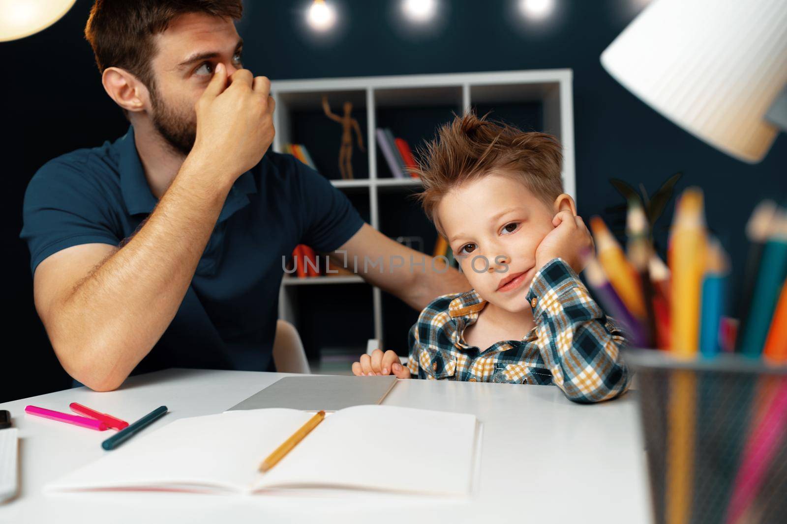 Dad and son doing school homework together sitting at the table