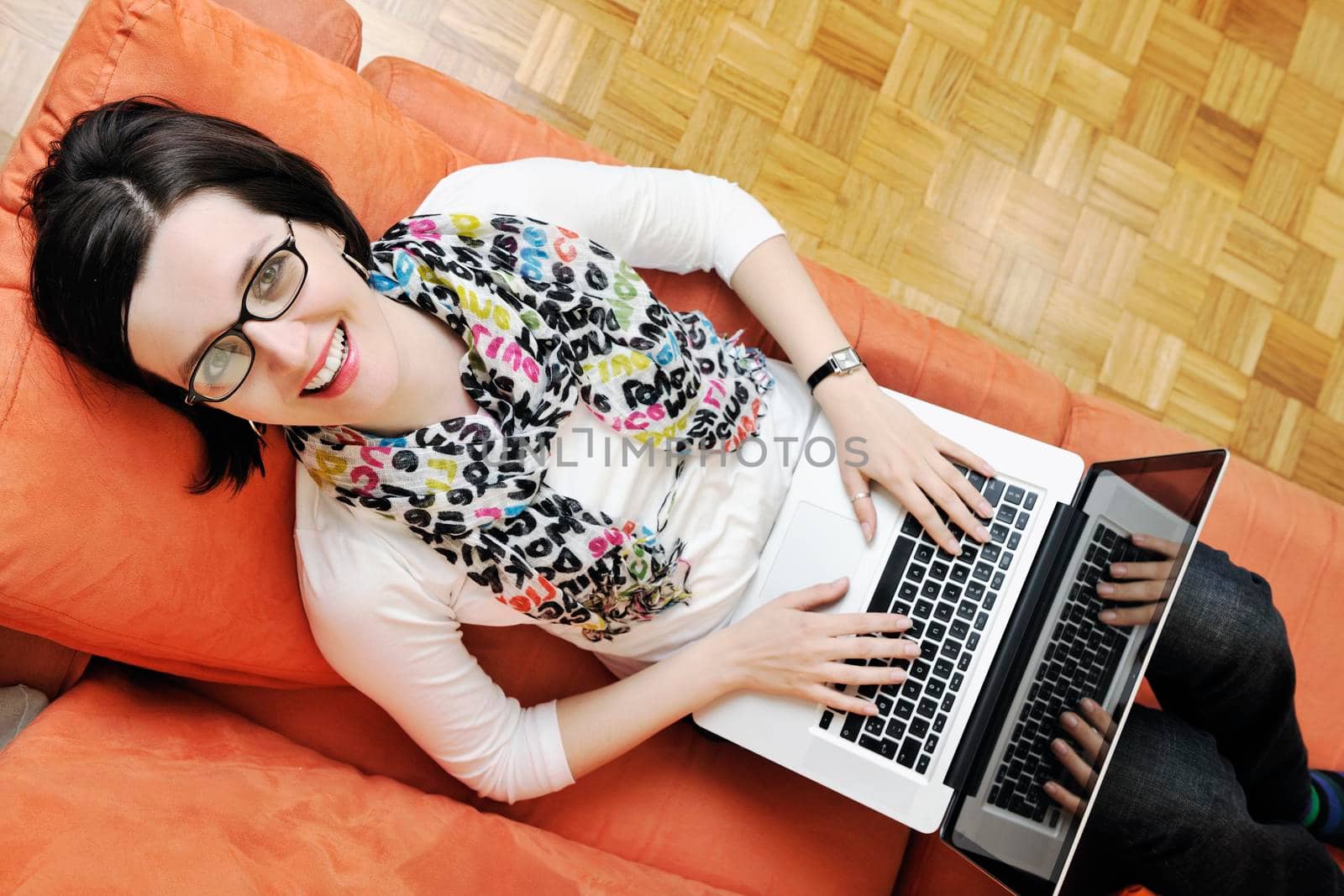 young business woman in casual clothes working on laptop computer on orange sofa isolated on white