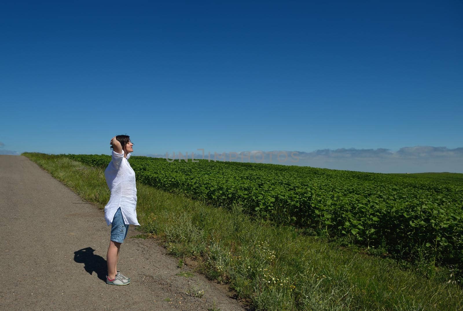 Young happy woman in green field with blue sky in background