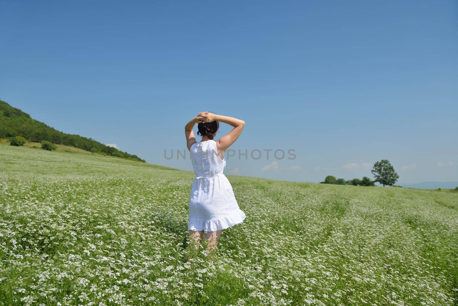 Young happy woman in green field with blue sky in background