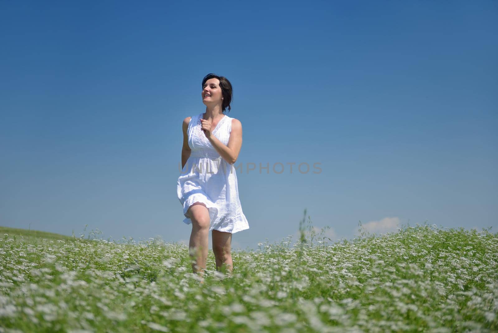 Young happy woman in green field with blue sky in background