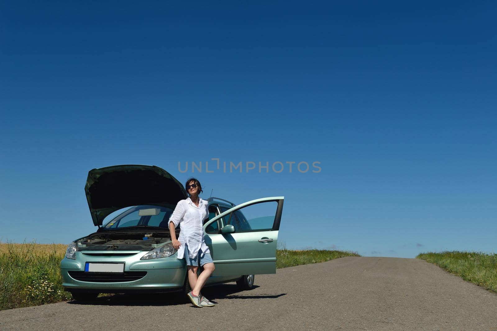 portrait of young beautiful woman with broken car outdoor