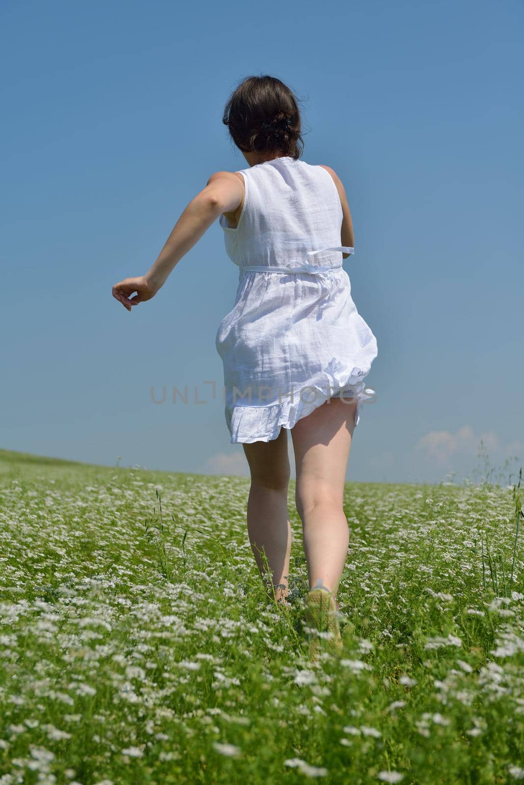 Young happy woman in green field with blue sky in background