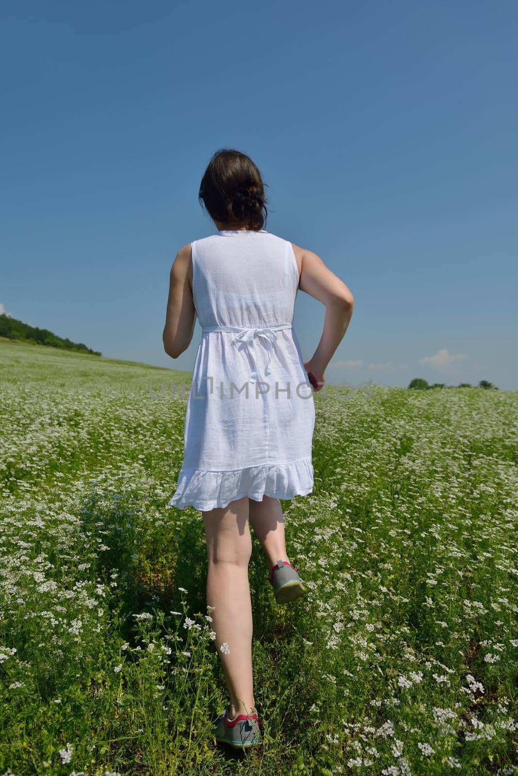 Young happy woman in green field with blue sky in background