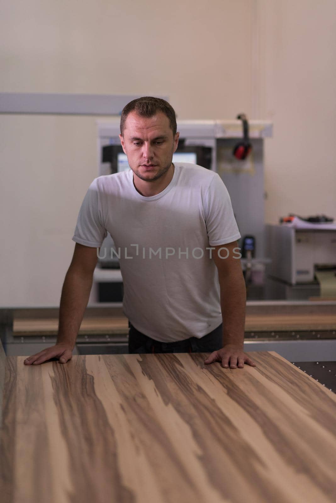 Young worker works in a factory for the production of wooden furniture