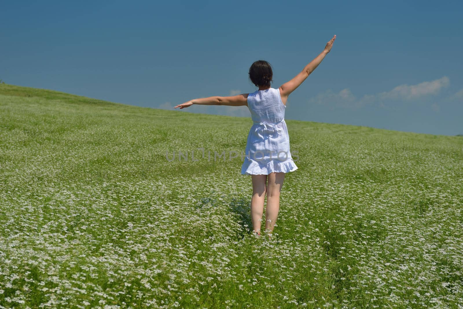 Young happy woman in green field with blue sky in background