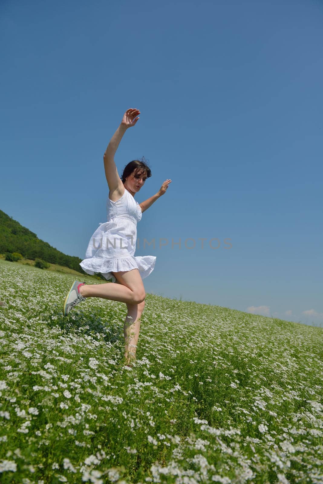 Young happy woman in green field with blue sky in background