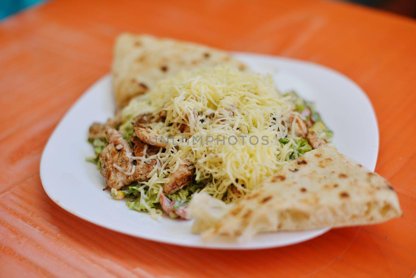 woman eat tasty chicken salad with fresh vegetables and cheese in retro kitchen