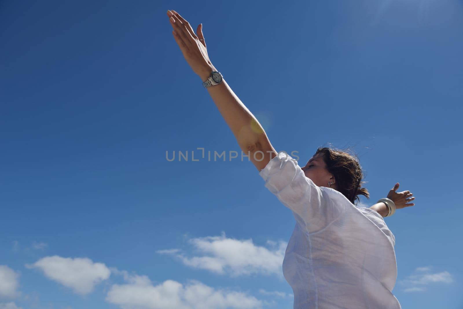 happy young woman with spreading arms to sky by dotshock