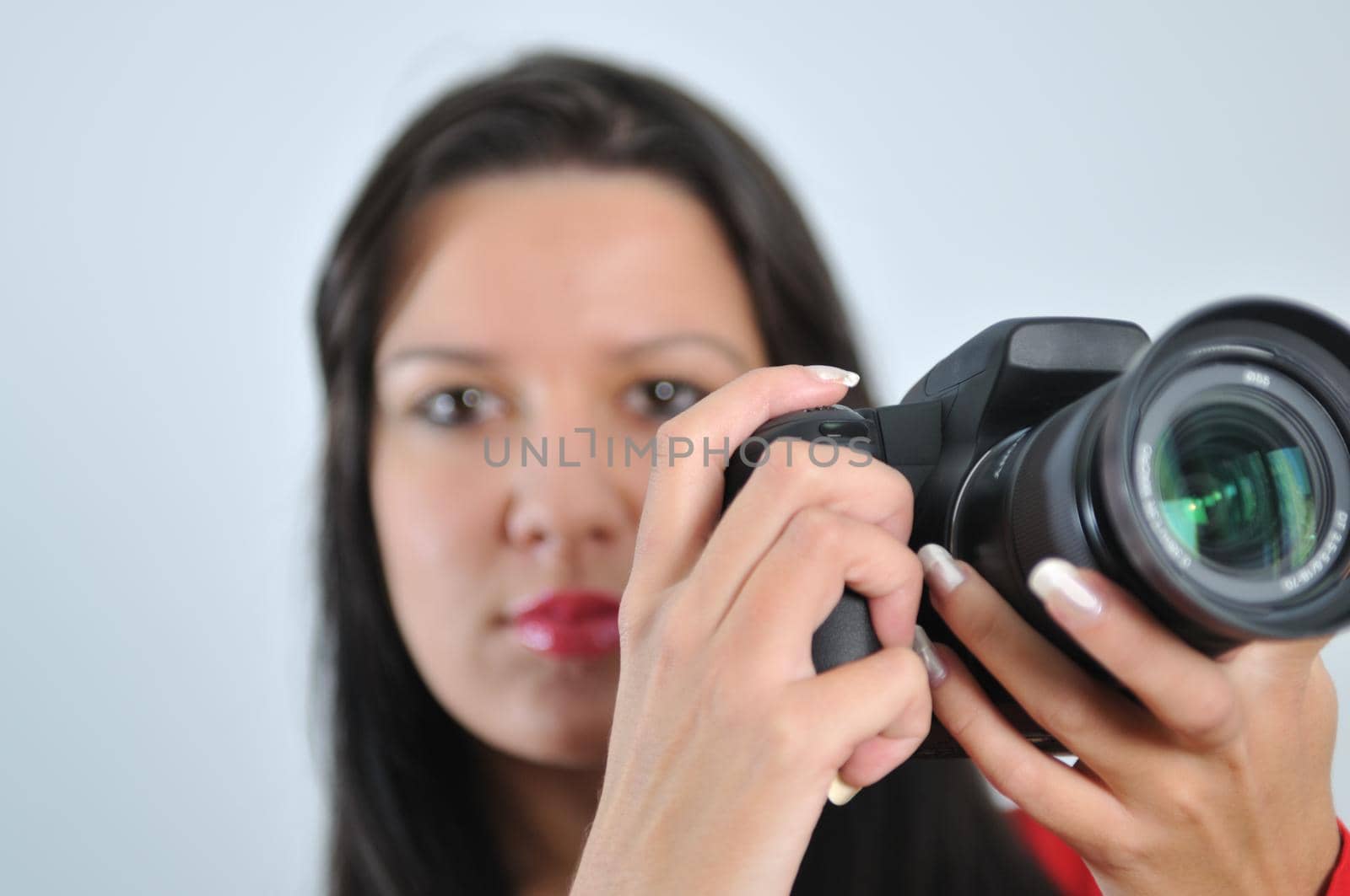 Young woman holding camera in hand taking picture isolated by dotshock