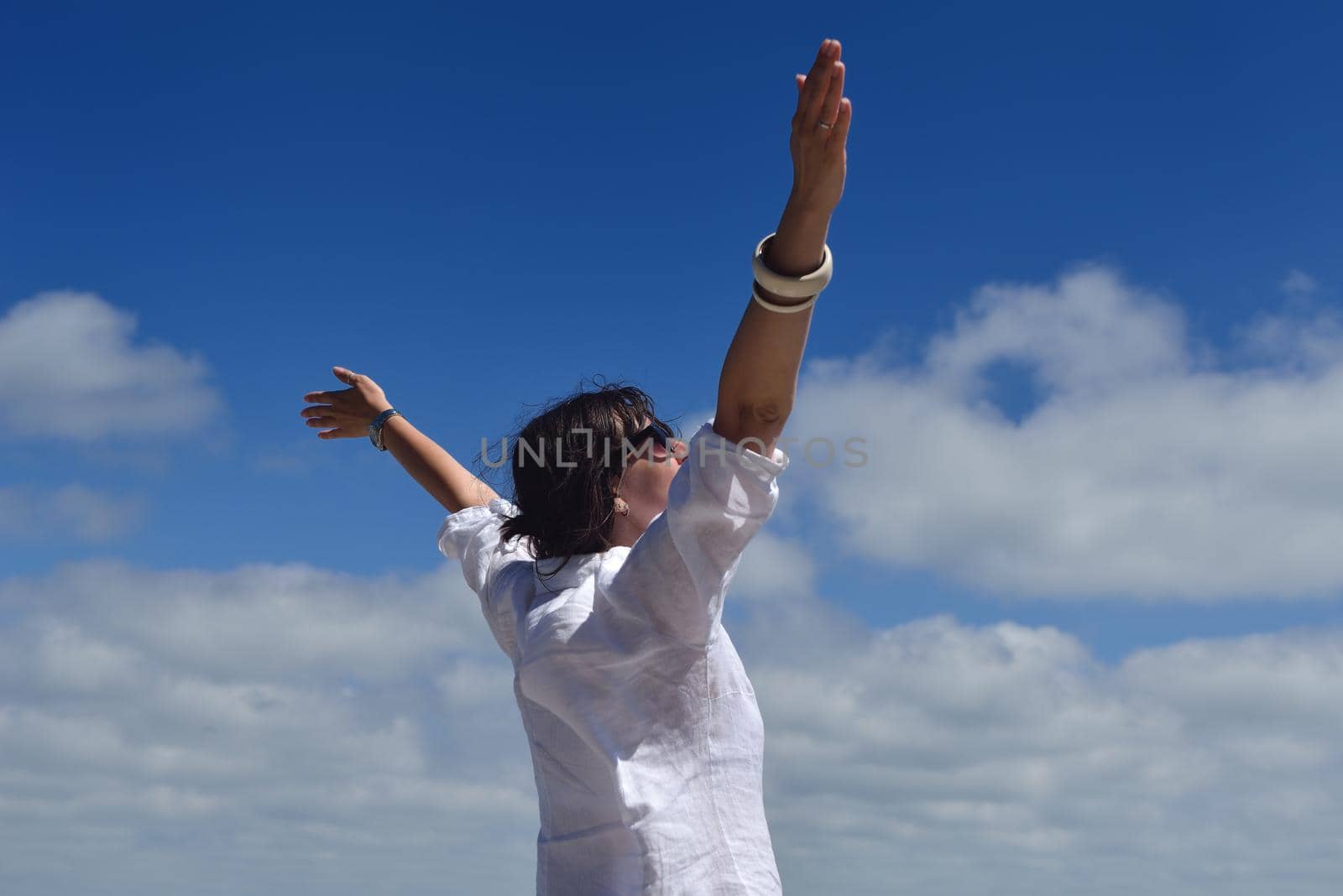 happy young woman with spreading arms to sky by dotshock