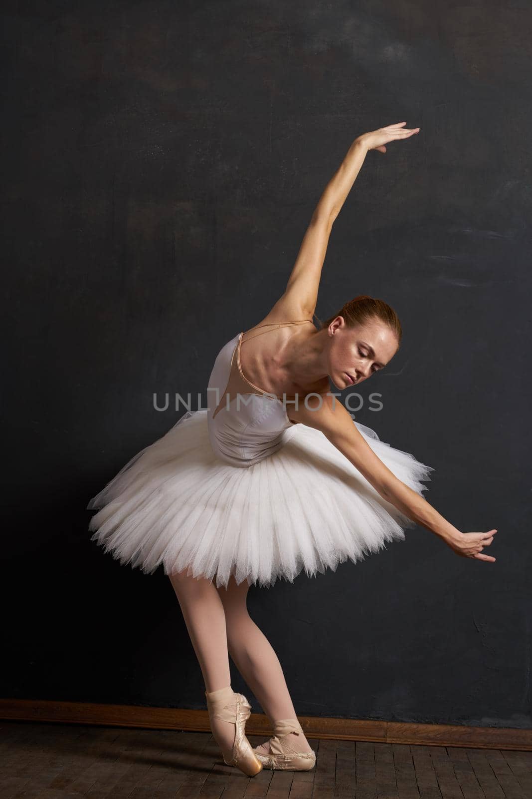 woman ballerina in a white tutu dance posing performance dark background. High quality photo
