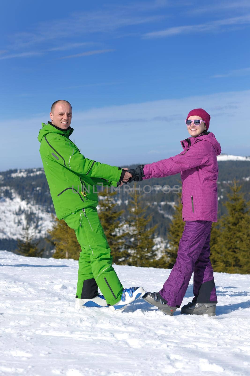 Portrait of happy couple at beautiful mountain on winter sunny day with blue sky and snow in background