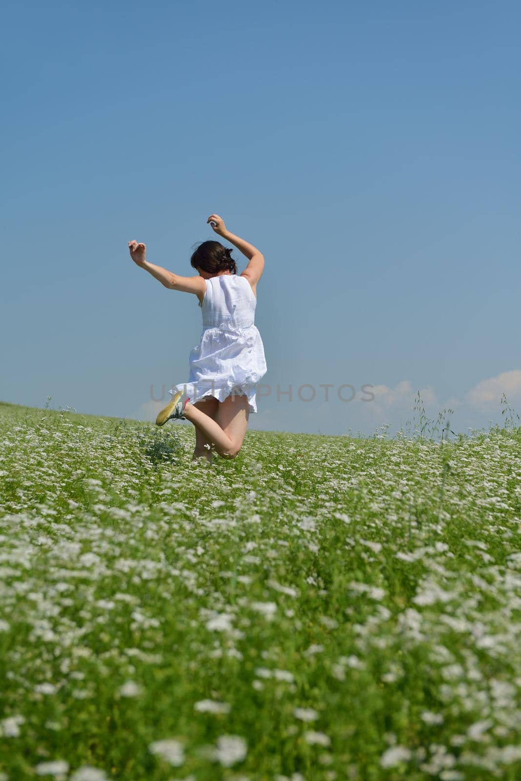 Young happy woman in green field with blue sky in background