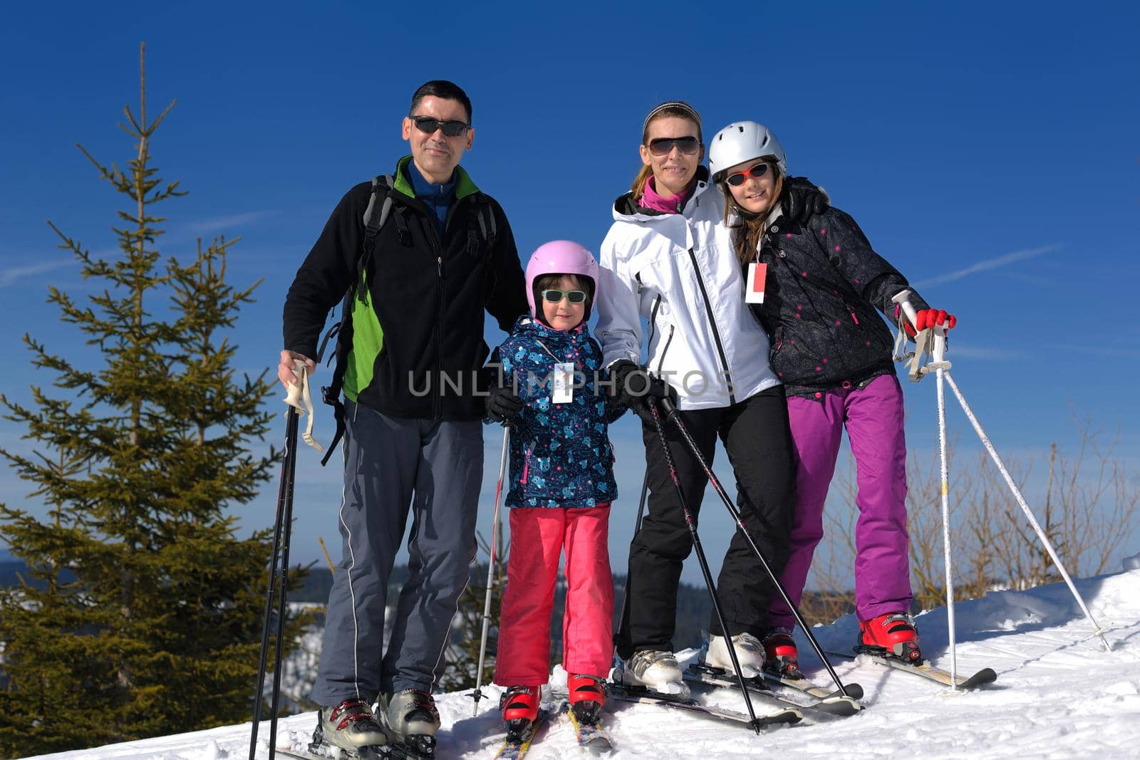 portrait of happy young family at beautiful winter sunny day with blue sky and snow in background