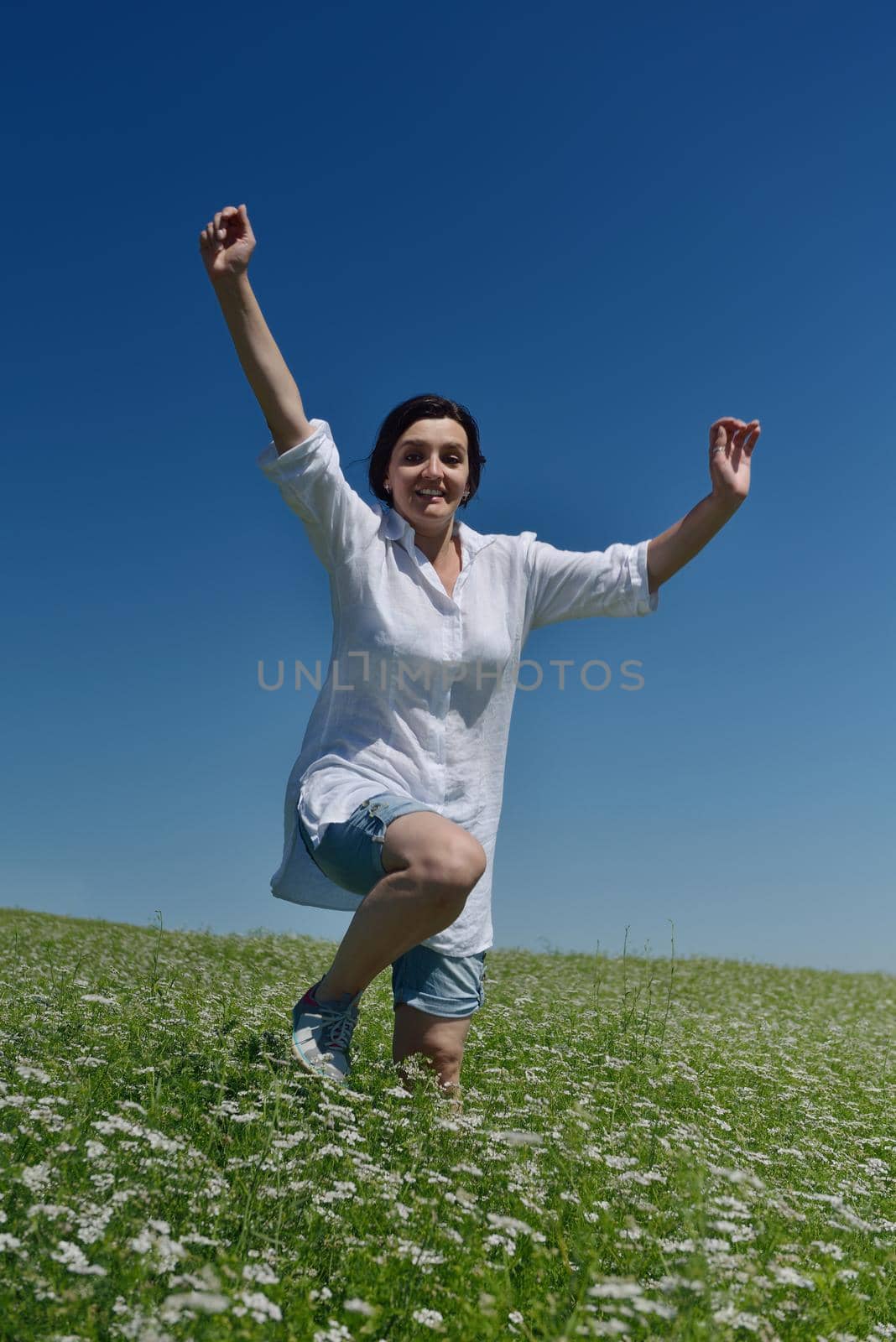 Young happy woman in green field with blue sky in background