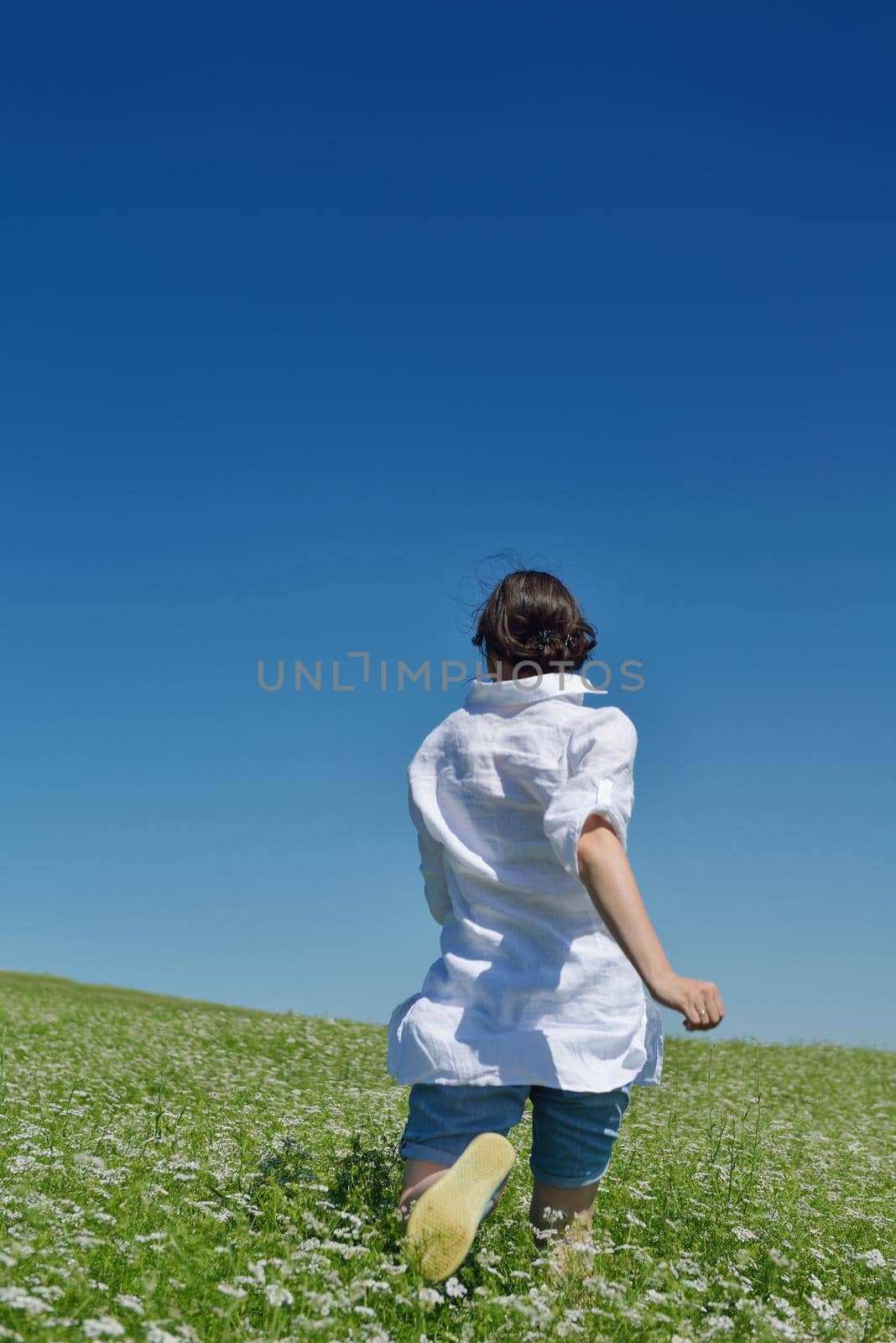 Young happy woman in green field with blue sky in background