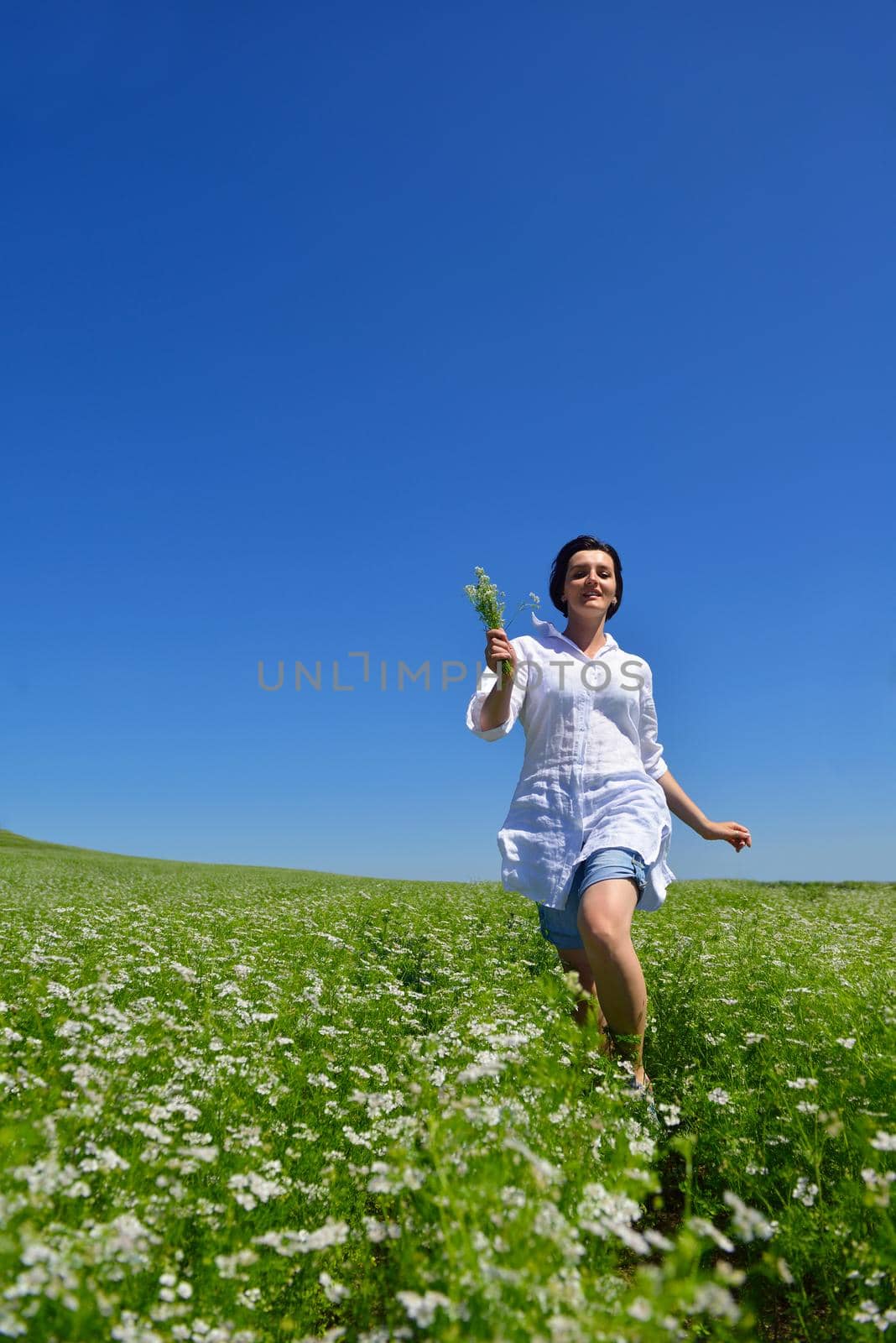 Young happy woman in green field with blue sky in background