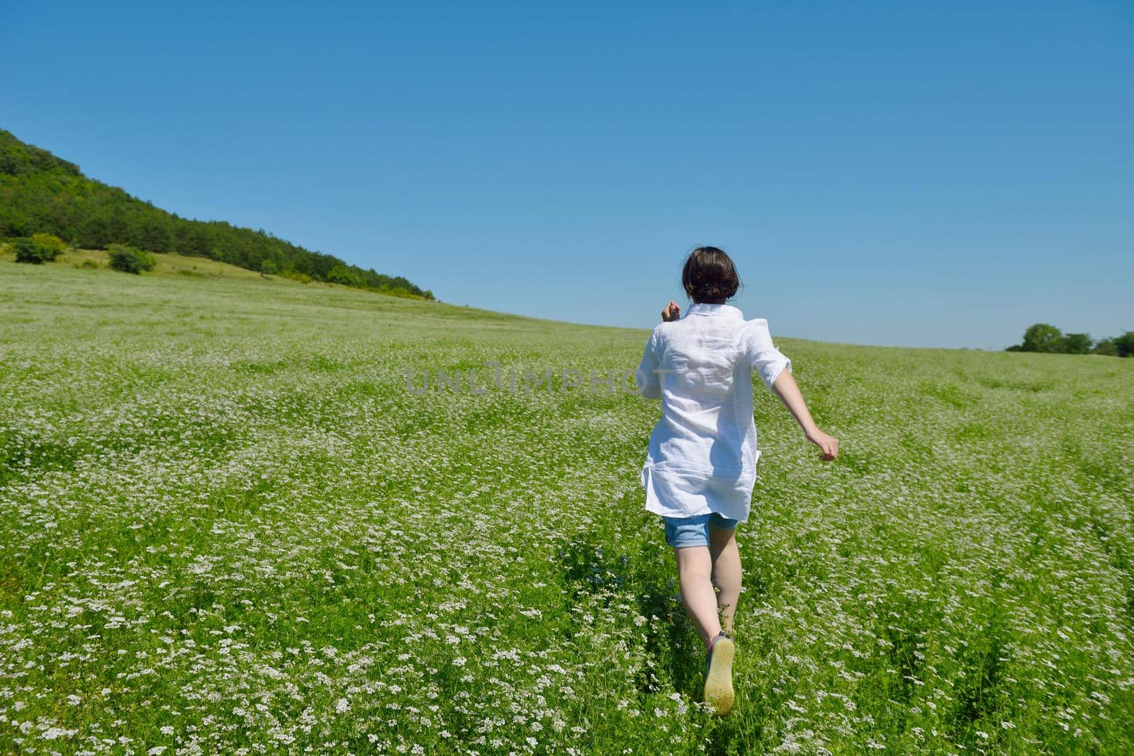 Young happy woman in green field with blue sky in background