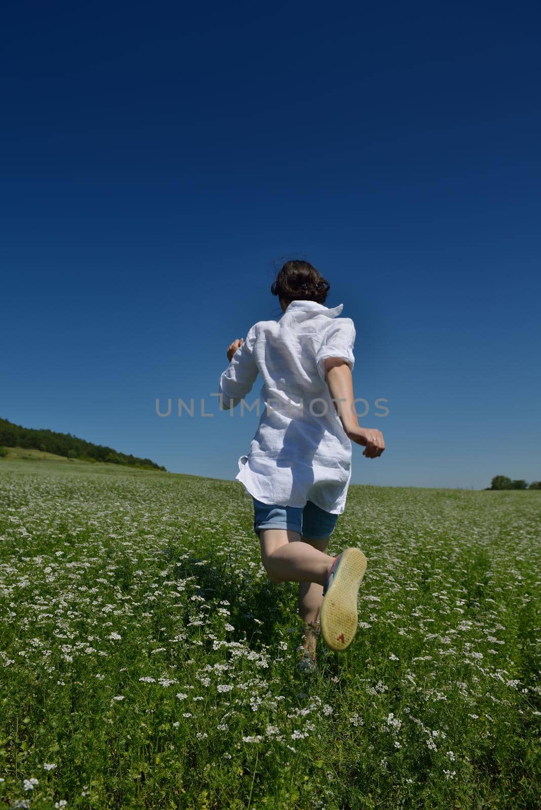 Young happy woman in green field with blue sky in background