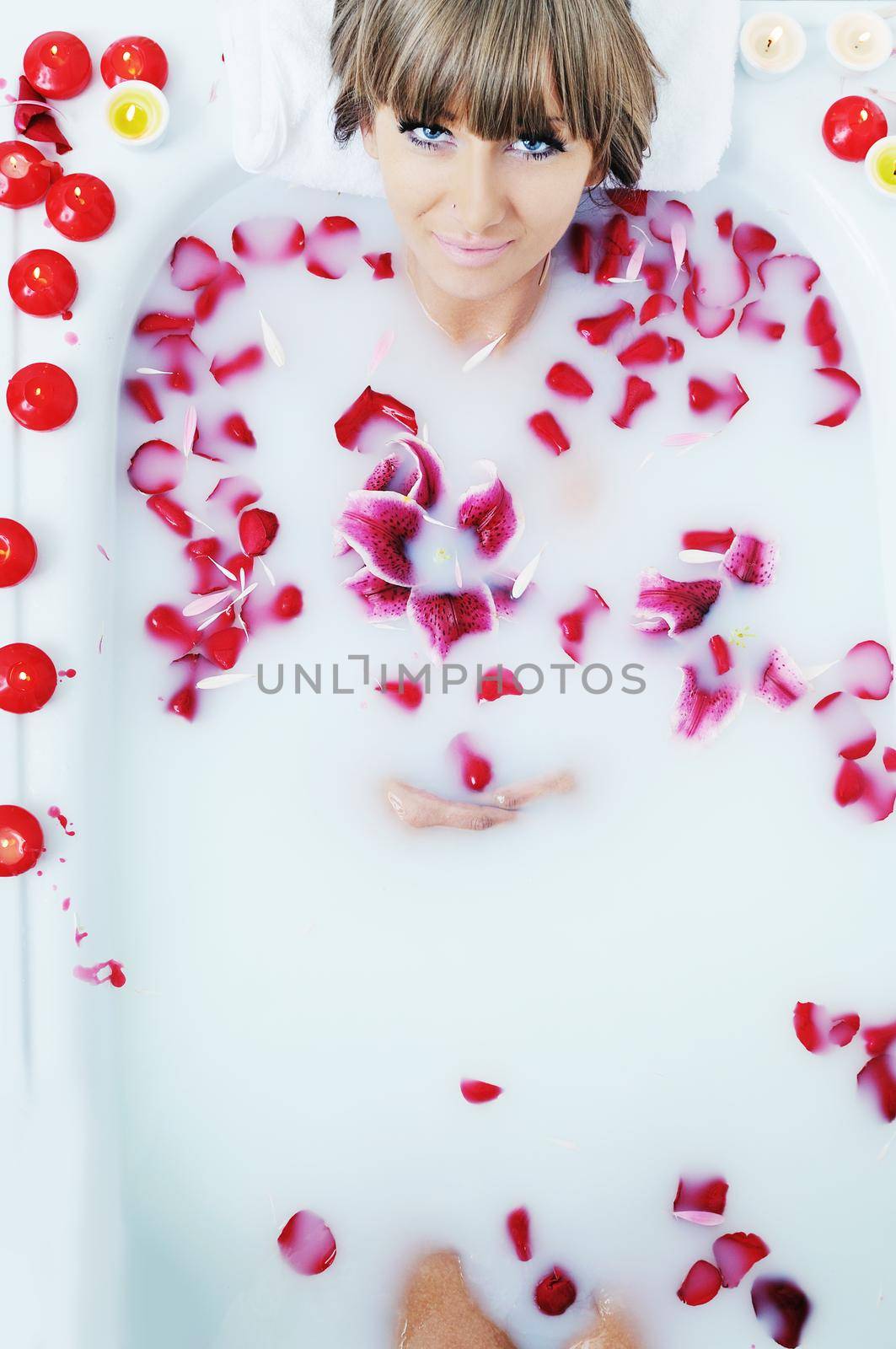 woman beauty spa and wellness treathment with red flower petals in bath