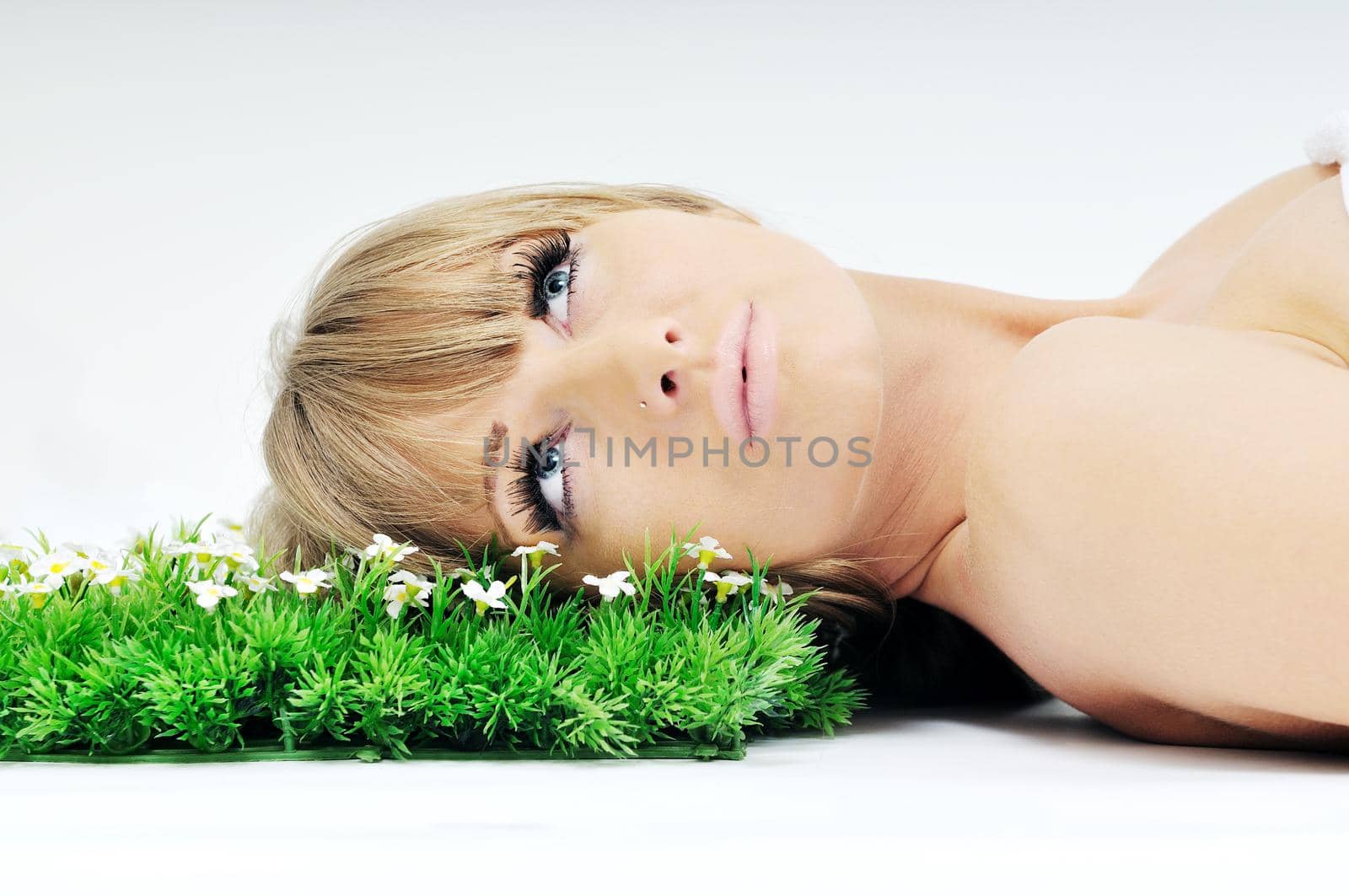 beautiful blonde woman face isolated on white with small green peace of grass