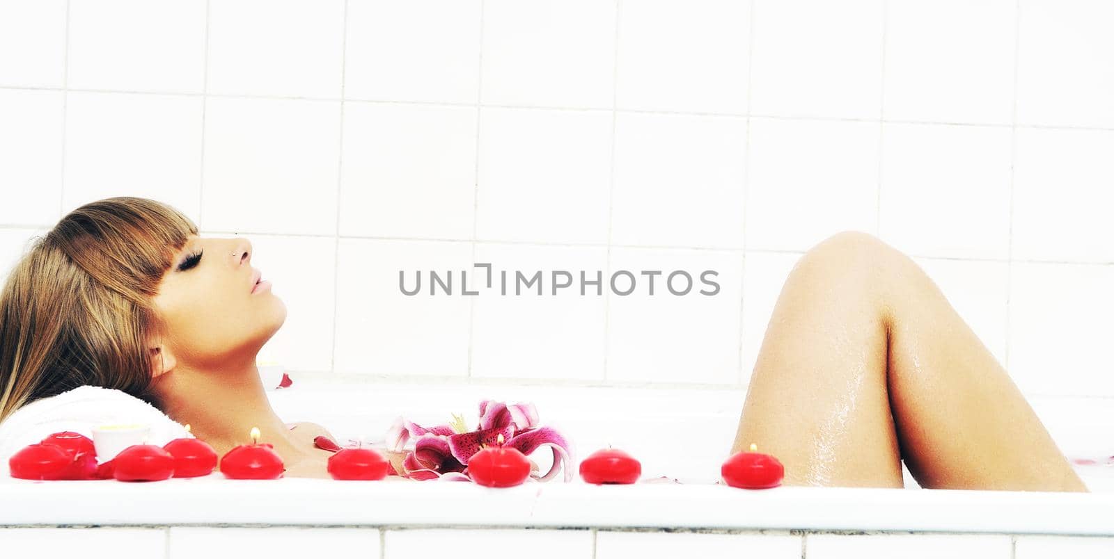 woman beauty spa and wellness treathment with red flower petals in bath