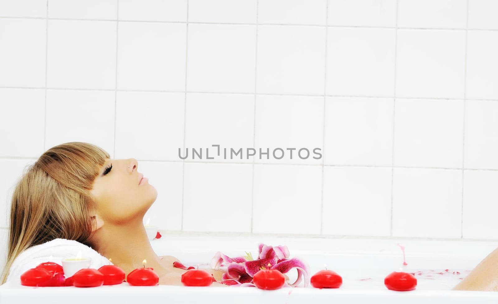 woman beauty spa and wellness treathment with red flower petals in bath