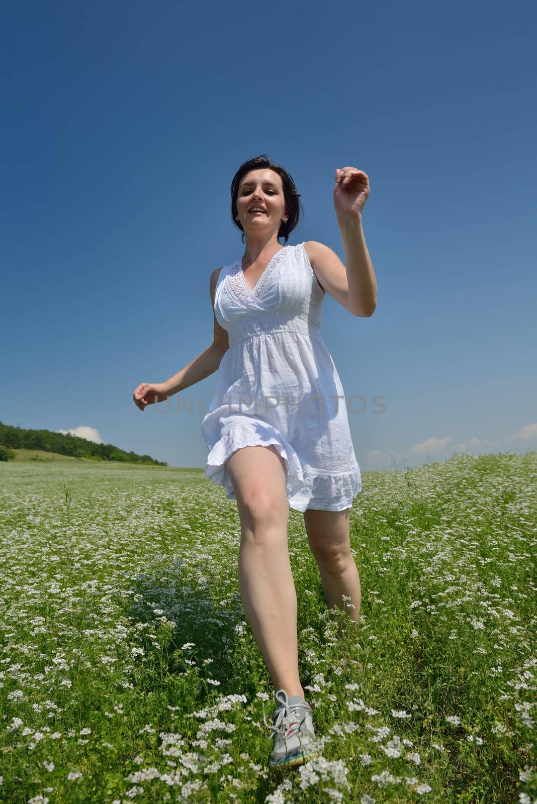 Young happy woman in green field with blue sky in background