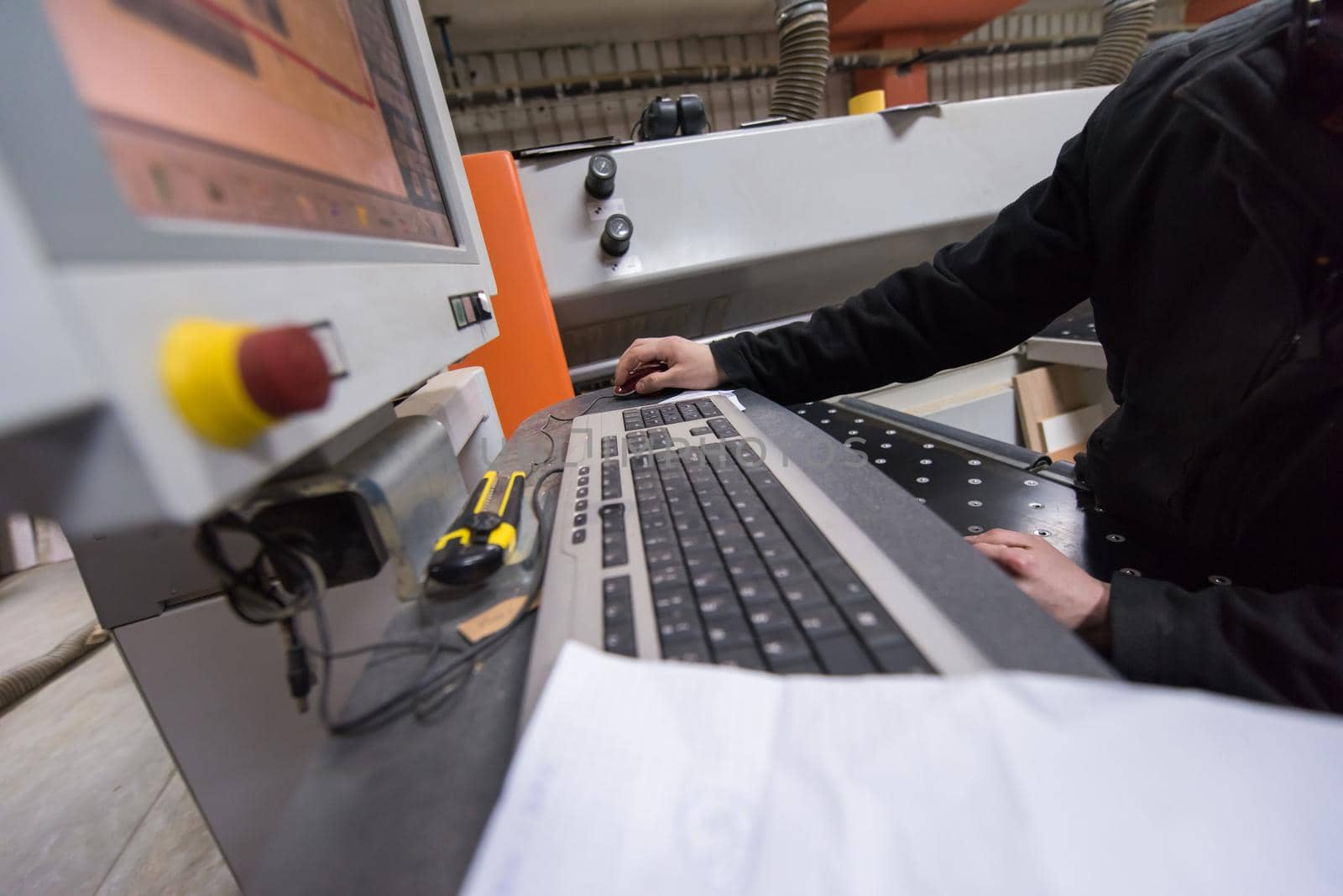 two young carpenters calculating and programming a cnc wood working machine in workshop. wood workers preparing a computer program for CNC machine at big modern carpentry