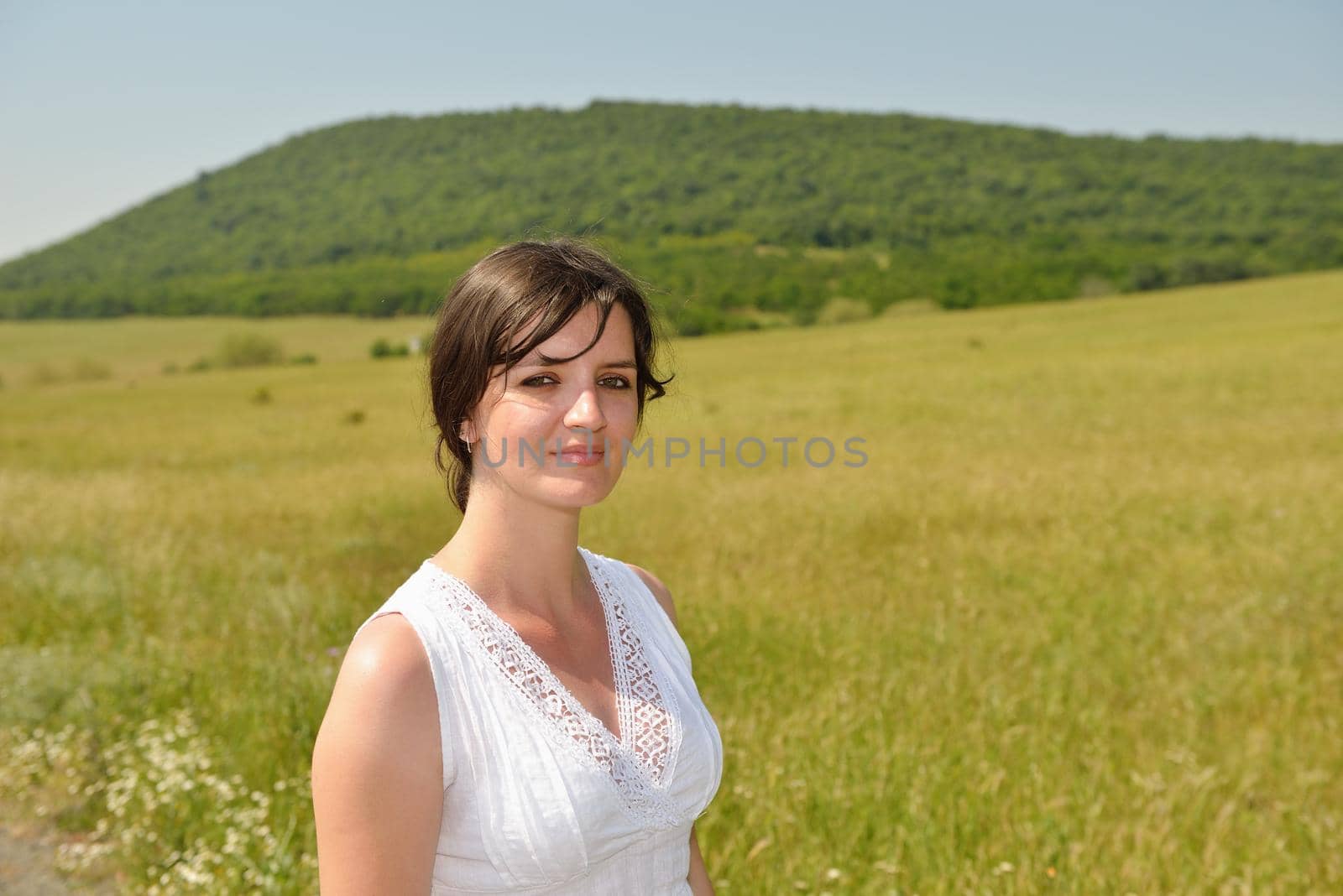 Young happy woman in green field with blue sky in background