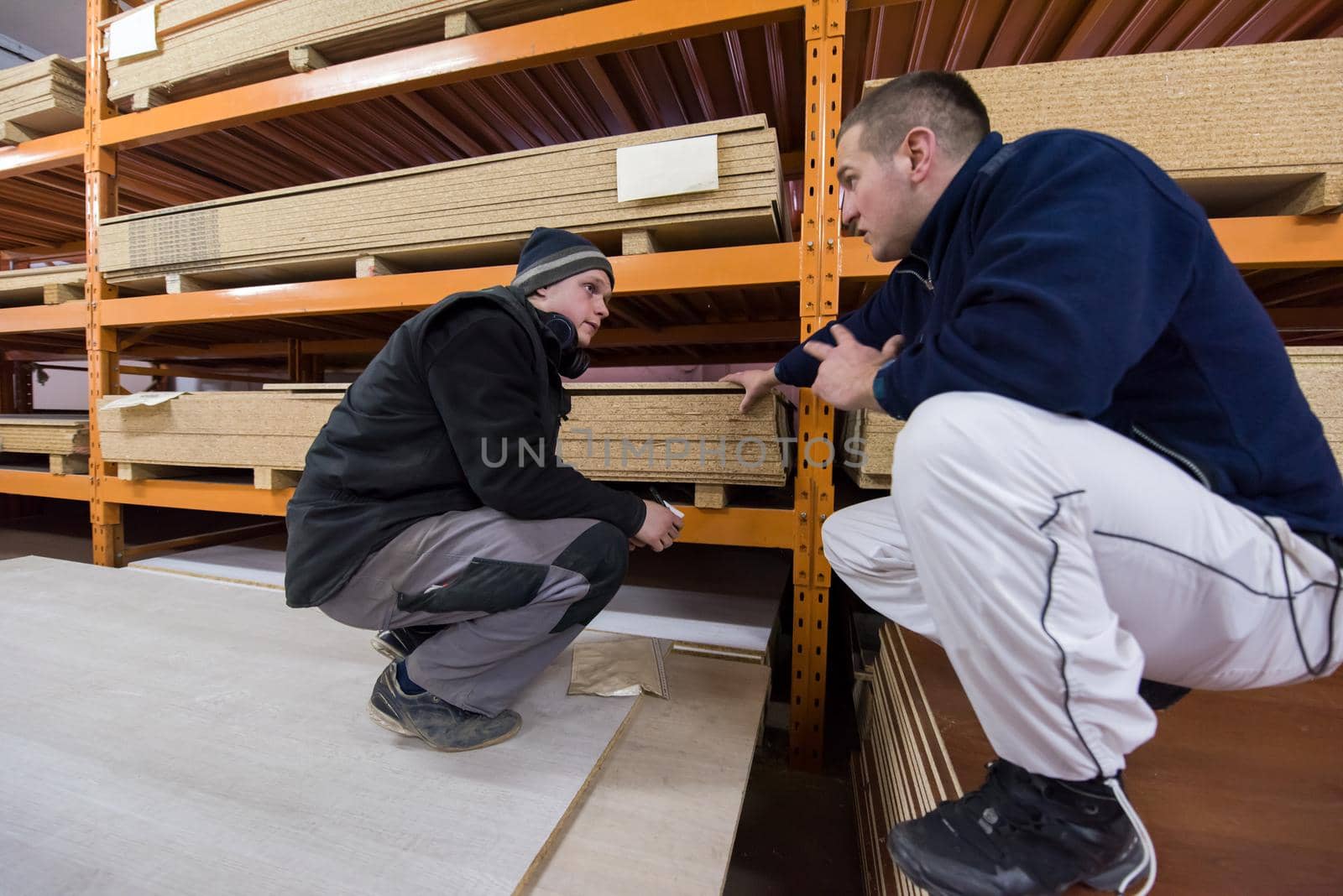 two young carpenters writing new prices while working together in big modern carpentry High quality wood concept