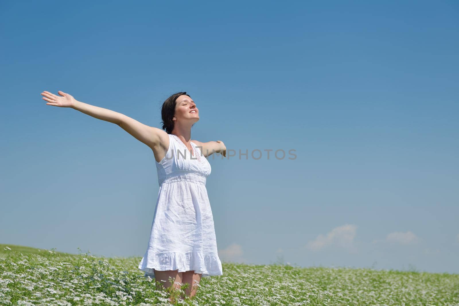 Young happy woman in green field with blue sky in background