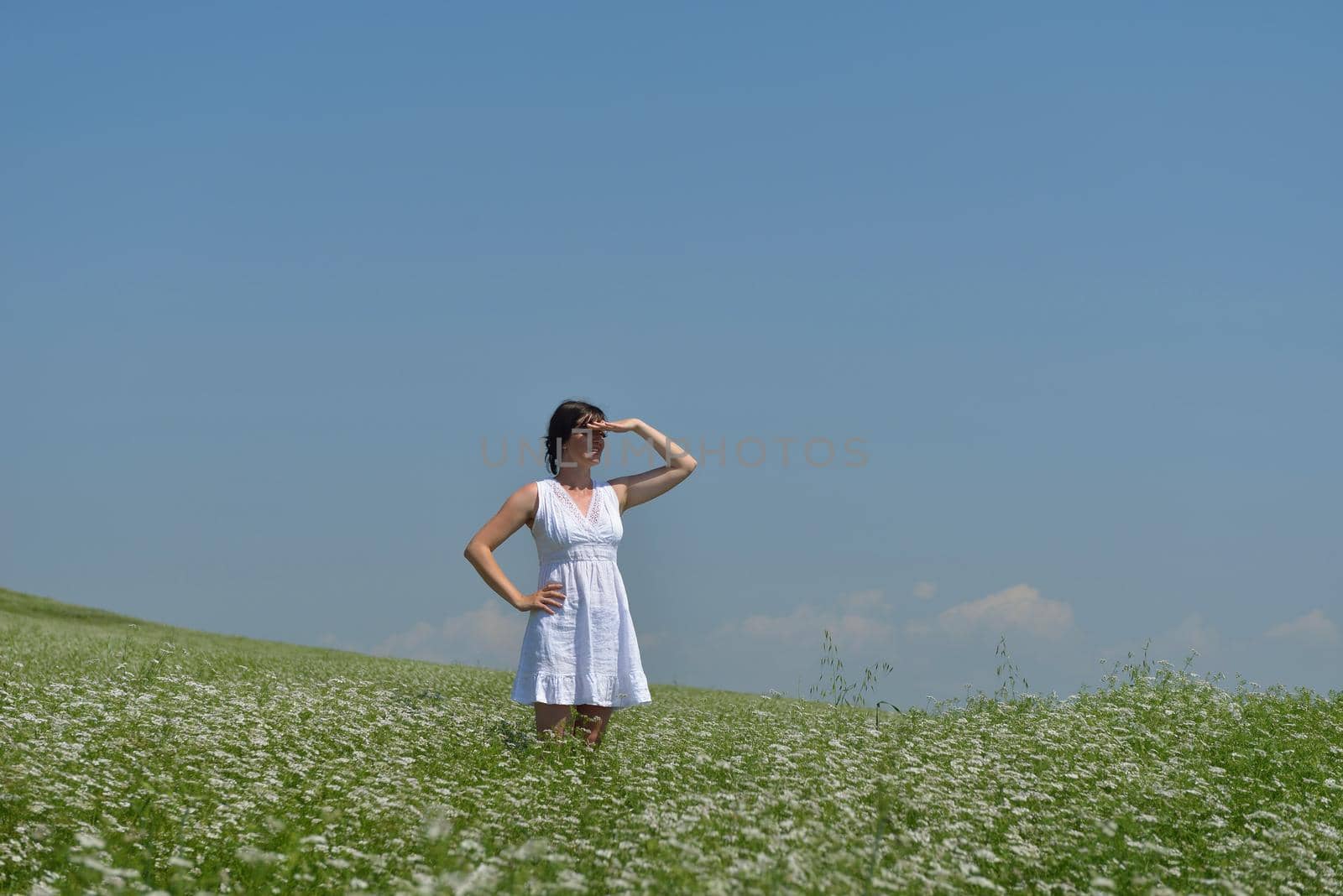 Young happy woman in green field with blue sky in background